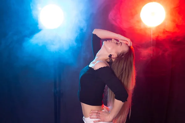 Vida nocturna y concepto de club - mujer joven bailando en la oscuridad bajo las luces —  Fotos de Stock