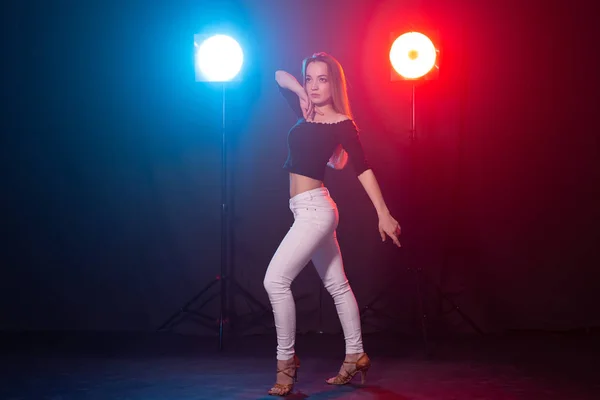 Vida nocturna y concepto de club - mujer joven bailando en la oscuridad bajo las luces —  Fotos de Stock