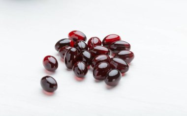 Beyaz masa arka planında kırmızı haplar. Vitamin ve mikroelementlerin ilaç kavramı. Tedavi ve önleme.