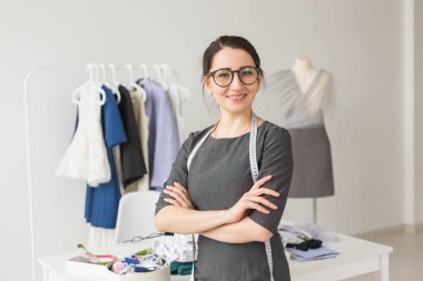 Terzi, moda tasarımcısı ve terzi kavramı - giysi raf elbise arka plan ile genç terzi kadın