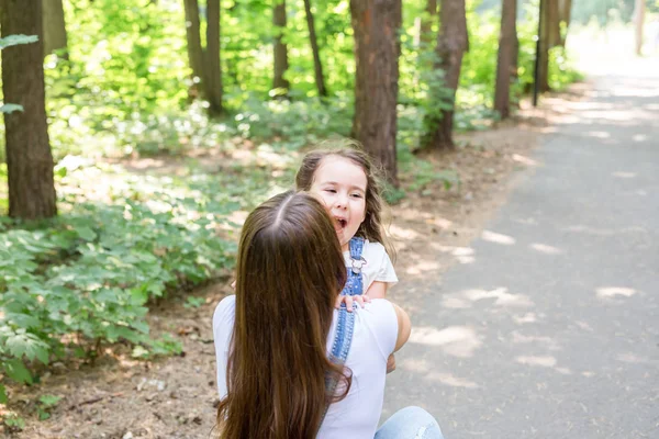 Концепция семьи и природы - молодая женщина обнимает маленькую девочку в парке — стоковое фото