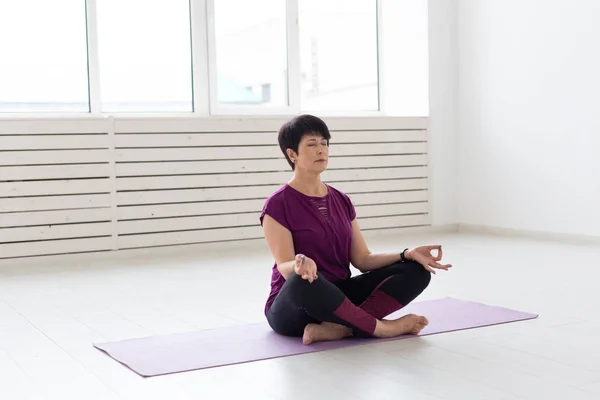 Yoga, harmony, people concept - Middle aged woman sitting in lotus position