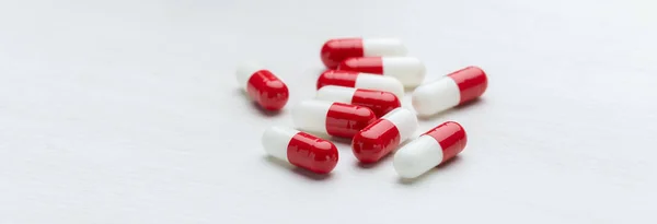 Pastillas rojas y blancas sobre un fondo de mesa blanco con espacio para copiar. Concepto de medicación de vitaminas y microelementos. Tratamiento y prevención . —  Fotos de Stock