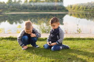 Çocuk ve doğa kavramı - çim üzerinde doğa arka plan üzerinde oturan iki kardeş