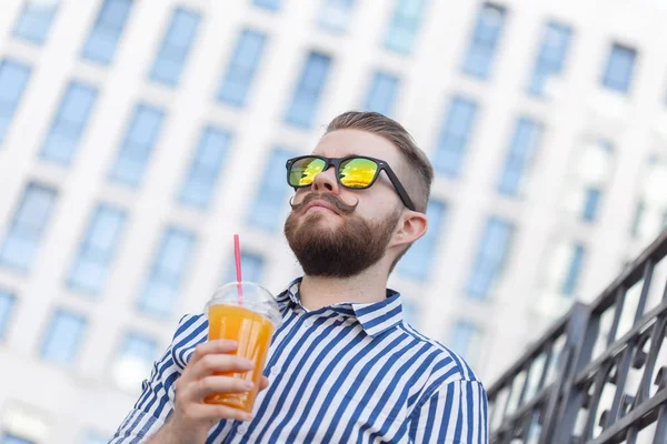 Retrato de vista inferior de un hombre hipster joven con estilo en vasos de espejo con jugo en el fondo del centro de negocios. Vacaciones urbanas en el concepto de fin de semana . — Foto de Stock