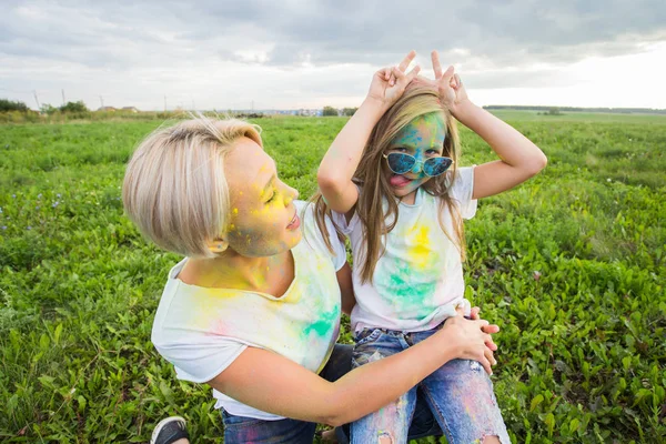 Štěstí, Holi festival a svátků koncepce - matka a její dcera pokryté barevný prášek s úsměvem nad přírodní pozadí — Stock fotografie