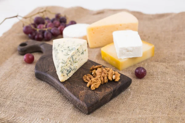 Fresh products. Cheese, brie, Camembert, grapes and nuts on rustic table.