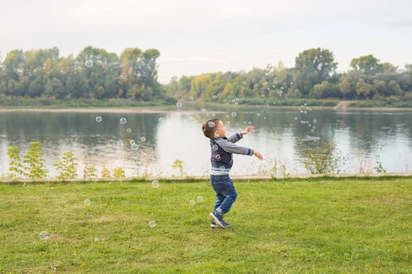 Crianças e conceito de natureza - Menino tentando pegar bolhas de sabão — Fotografia de Stock