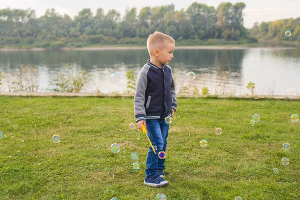 Crianças e conceito de natureza - Menino tentando pegar bolhas de sabão — Fotografia de Stock