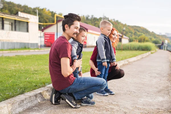 Elternschaft, Kindheit und Familienkonzept - Eltern und zwei männliche Kinder gehen durch den Park und schauen sich etwas an — Stockfoto