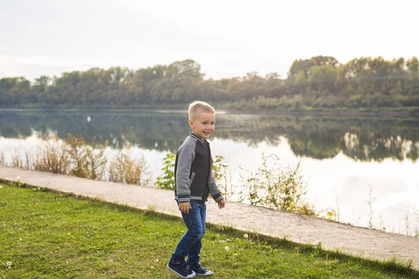 Children and childhood concept - young boy walking near the river — Stock Photo, Image