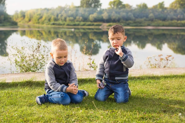 Çocuk ve doğa kavramı - çim üzerinde doğa arka plan üzerinde oturan iki kardeş