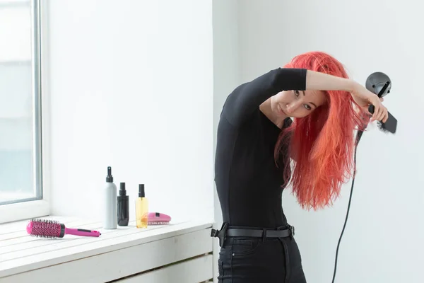 Hairdresser, style, people concept - woman is blowing dry her colored hair