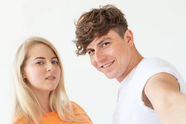 Charmig ungt par Söt blond flicka flicka ta en selfie poserar över vit bakgrund. Koncept ett ungt par tonåringar eller Millennials i kärlek. — Stockfoto