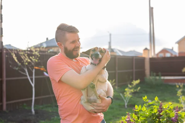 동물, 애완 동물 및 사람들 개념 - 잭 러셀 테리어와 캐주얼 복숭아 컬러 티셔츠에 웃는 남자 — 스톡 사진