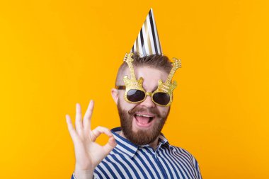 Sakallı çılgın genç pozitif hipster adam mutlu sarı bir arka plan üzerinde gülüyor. Tatil ve satış kavramı