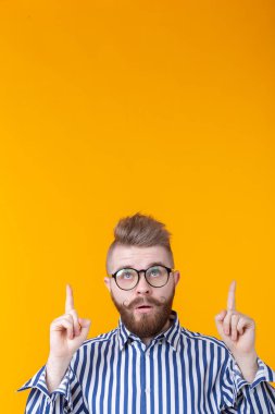 Çözüm burada. Yakışıklı komik genç adam kopya alanı işaret ve sarı arka plan karşı dururken yukarı bakıyor