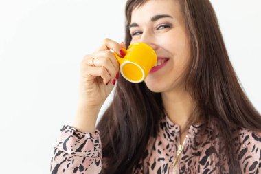 Elinde tutan eğlenceli genç esmer kadın beyaz bir arka planda poz küçük sarı kupa. Sabah kahvesi konsepti.