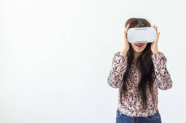 Sanal gerçeklik gözlüğü takan ve kopya alanı ile beyaz bir arka plan karşı dururken bir oyun oynarken güzel genç kadın. Fütürizm ve yeni teknolojiler kavramı.