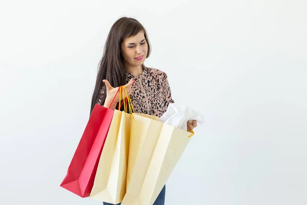 Joven morena alegre sosteniendo bolsas de compras posando sobre un fondo blanco con espacio para copiar. Concepto de descuentos y ventas en el centro comercial . — Foto de Stock