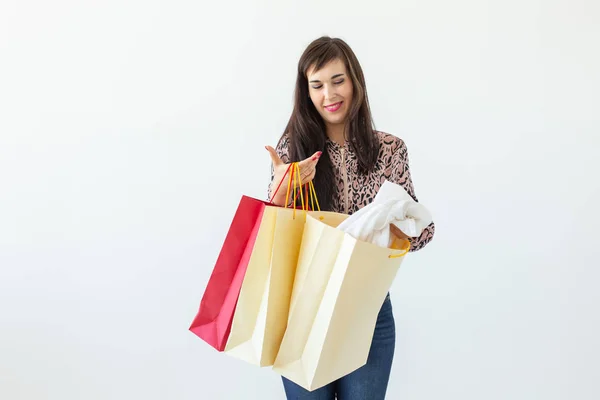 Θετική νεαρή κομψή μελαχρινή γυναίκα κρατώντας σακούλες που ποζάρουν σε λευκό φόντο με χώρο αντιγραφής. Εμπορική έννοια σε ένα εμπορικό κέντρο. — Φωτογραφία Αρχείου