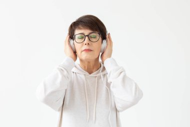 Hobi, ilgi alanları ve insan kavramı - Güzel kadın 40-50 yaşında beyaz arka planda büyük kulaklık müzik dinleme