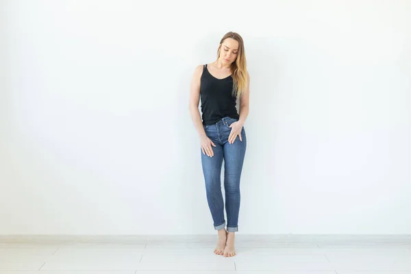 Estilo, concepto de la gente - mujer joven en jeans y camisa negra de pie sobre el fondo blanco con espacio para copiar —  Fotos de Stock
