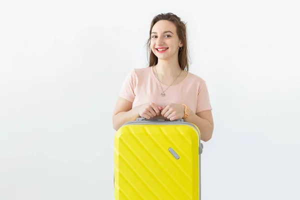 Portrait d'une belle jeune femme brune avec une valise jaune dans les mains posant sur un fond blanc. Concept de voyage et de tourisme . — Photo