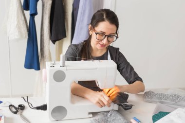 insanlar, moda ve showroom konsept - genç moda tasarımcısı bir dikiş makinesi giysilerini diker.