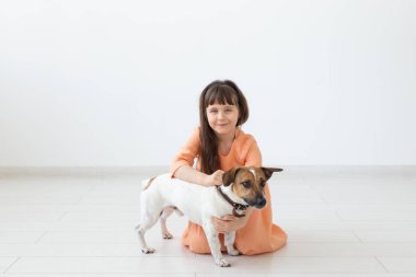 Çocuklar ve evcil hayvan sahibi kavramı - küçük çocuk kız sevimli köpek Jack Russell Terrier ile katta oturan
