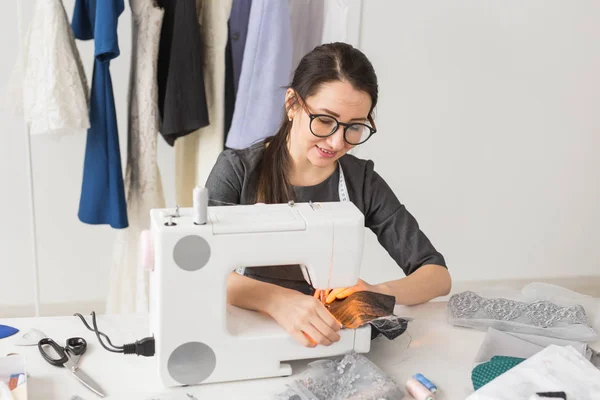 Gente y concepto de moda - Mujer modista joven cose ropa en la máquina de coser — Foto de Stock