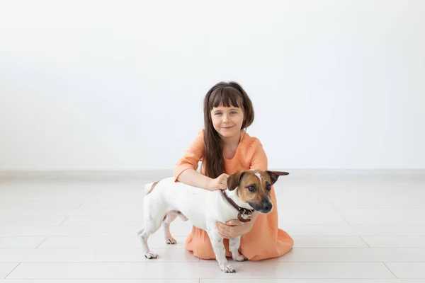 Děti a domácí zvířata koncept-malá holčička, která sedí na podlaze s roztomilým štěňátka Jack Russell teriér — Stock fotografie