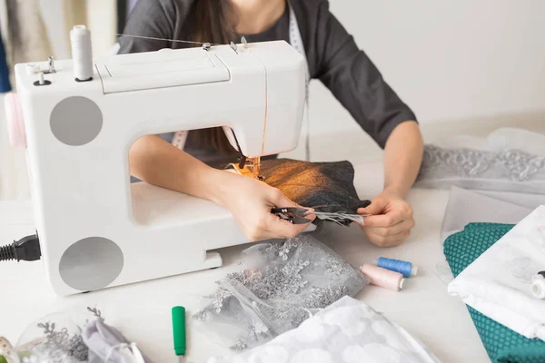 Concepto de personas, moda y sala de exposición - joven diseñador de moda cose la ropa en una máquina de coser de cerca — Foto de Stock