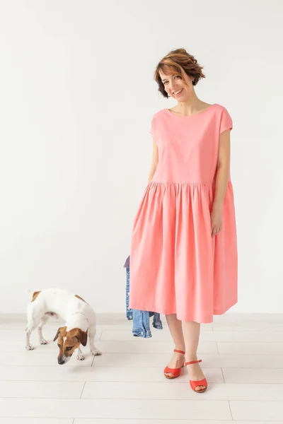Háziállat tulajdonos koncepció-fiatal nő rózsaszín ruhában Jack Russell terrier kutya a fehér háttér — Stock Fotó