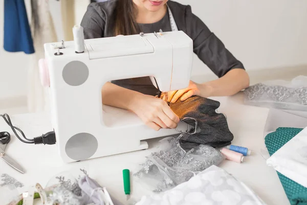 People and fashion concept - Young dressmaker woman sews clothes on sewing machine — Stock Photo, Image