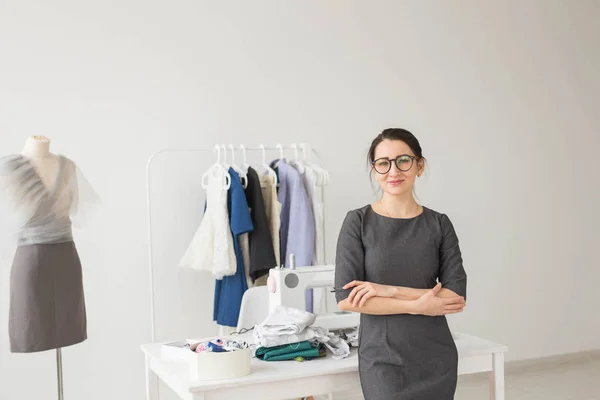 Naaister, mode-ontwerper en kleermaker concept - jonge naaister vrouw over kleding rek met jurken achtergrond — Stockfoto