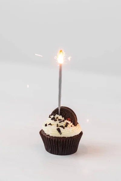 Comida, panadería, vacaciones, feliz cumpleaños y el concepto de postres delicioso cupcake con espumoso y galletas en la mesa blanca —  Fotos de Stock