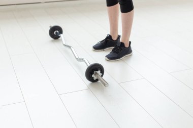 Egzersizyapmak için geniş parlak spor salonunda barbell ile tanımlanamayan genç kız. Güçlü kaslar ve sağlıklı bir vücut kavramı.