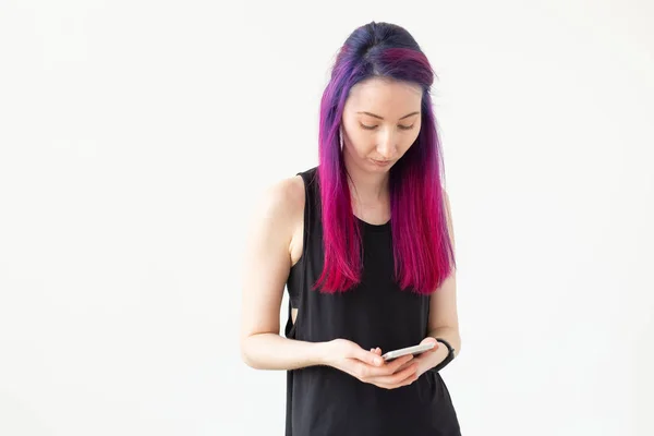 Jolie jeune fille métissée aux cheveux violets compte les calories brûlées à l'aide d'une application sur son smartphone tout en étant assise sur un tapis de sport dans la salle de gym. Concept yoga et fitness . — Photo