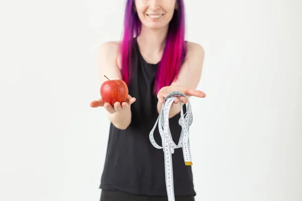 Giovane ragazza asiatica offuscata hipster capelli colorati tenendo in mano un metro e mela posa su uno sfondo bianco. Un concetto di alimentazione sana. Spazio pubblicitario . — Foto Stock
