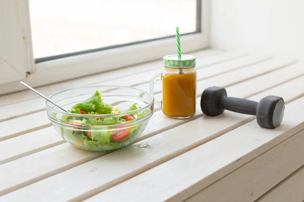 Salade de légumes et smoothies de fruits et haltère reposent sur un rebord de fenêtre blanc. Concept d'un mode de vie sain activité physique et bonne alimentation . — Photo