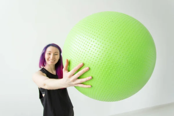 Niña alegre positiva borrosa hipster sosteniendo una pelota verde en sus brazos durante las clases en el gimnasio. Concepto de yoga y pilates y fitness . — Foto de Stock