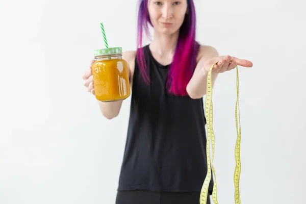 Carino giovane ragazza hipster razza mista con capelli colorati beve frullato di frutta prima di iniziare una lezione di yoga su uno sfondo bianco. Un concetto di stile di vita sano. Copyspase . — Foto Stock