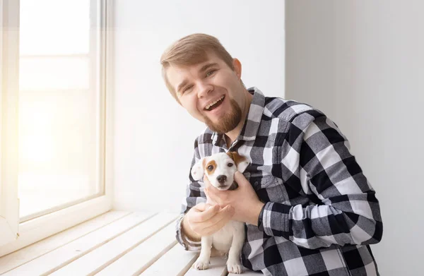 사람과 애완 동물 개념-창 배경 위에 개 잭 러셀 테리어를 들고 행복 한 사람 — 스톡 사진