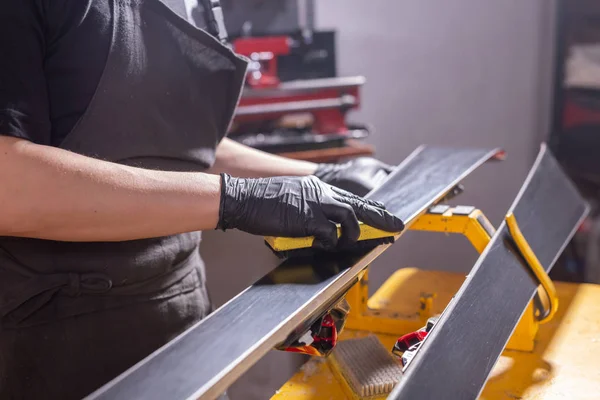 Concetto di lavoro e riparazione - mani di uomo che riparano lo sci strofinando una paraffina — Foto Stock