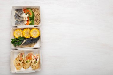 Balık ve sebze ile öğle yemeği kutuları üç çeşit beyaz bir masa üzerinde yatıyor. Kopya alanı. Sağlıklı beslenme konsepti