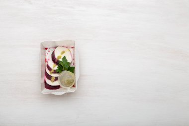 Beyaz peynir dilimleri ile haşlanmış pancar üst görünümü keçi peyniri yanında beyaz bir masada ekşi krema sosu ve maydanoz ile beyaz bir öğle yemeği kutusunda yatıyor. Protein atıştırmalık konsepti. Kopyalama alanı