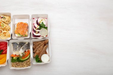 Öğle yemeği kutularında gün için sağlıklı yemekler seti kopya alanı ile beyaz bir masa üzerinde duruyor. Doğru beslenme menüsü kavramı proteinler, yağlar ve karbonhidratdengesi