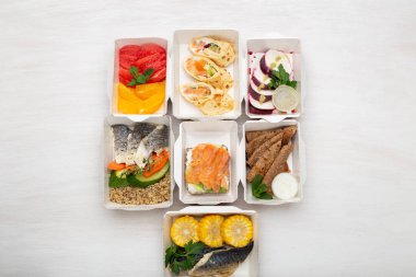 Öğle yemeği kutularında gün için sağlıklı yemekler seti beyaz bir masa üzerinde duruyor. Doğru beslenme menüsü kavramı proteinler, yağlar ve karbonhidratdengesi