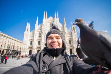 Kış seyahat, tatil ve kuşlar kavramı - selfie güvercinler yakınındaki Milan Katedrali Duomo di Milano, İtalya ile alarak genç komik adam.